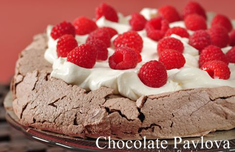 A chocolate pavlova topped with whipped cream and fresh raspberries